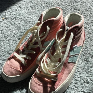 Rosa och mintgröna sneakers från Palladium - Snygga höga sneakers i rosa med mintgröna detaljer från Palladium. Skorna har vita snören och en rund tå. Perfekta för en avslappnad stil med en färgglad touch.