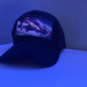 Svart keps med blixten - Cool svart keps med ett färgstarkt bilmotiv på framsidan. De är ju då en keps med blixten mcqueen. Endast använd 2-3 gånger då jag inte gillar att ha keps