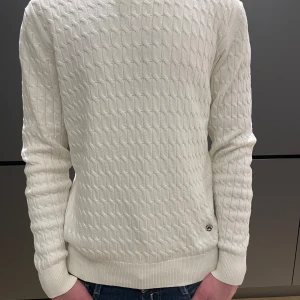 J.Lindeberg kabelstickad tröja - Riktigt schysst vit kabelstickad tröja från J.Lindeberg med riktigt skön merinoull o unikt metallemblem | Storlek M passar M | Skick 9/10 | Endast 249 kr, nypris 999kr | Priset är ej hugget i sten | Hör gärna av dig vid frågor och funderingar😊