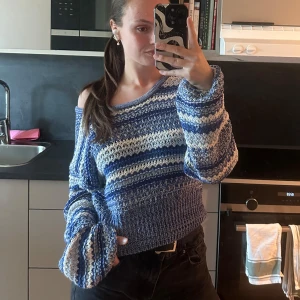 Blå och vit randig stickad tröja - Säljer en mysig blå och vit randig stickad tröja med en avslappnad passform. Tröjan har långa ärmar och en bred halsringning som kan bäras off-shoulder för en trendig look. Perfekt för kyliga dagar!