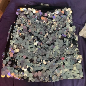 Glitter/Paljettkjolfrån Bik Bok - Snygg och glittrig paljettkjol från Bik Bok i storlek S. Kjolen är täckt med silverfärgade paljetter som ger en festlig look. Perfekt för att sticka ut på festen! 🪩✨