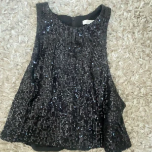 Svart paljettopp - Mer bilder finns privat om de söks, Snygg svart paljettopp som glittrar i ljuset. Perfekt för en utekväll, nyår eller fest. Toppen är ärmlös och har en lös passform som ger en bekväm känsla. Ett måste för garderoben om du vill sticka ut!