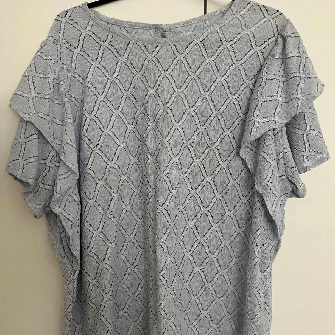 Ljusblå blus med volangdetaljer