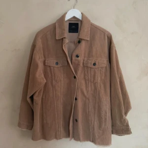 Beige manchesterjacka från Zara - Säljer en snygg beige manchesterjacka från Zara. Jackan har en klassisk design med knappar framtill och två bröstfickor. Perfekt för en stilren look.