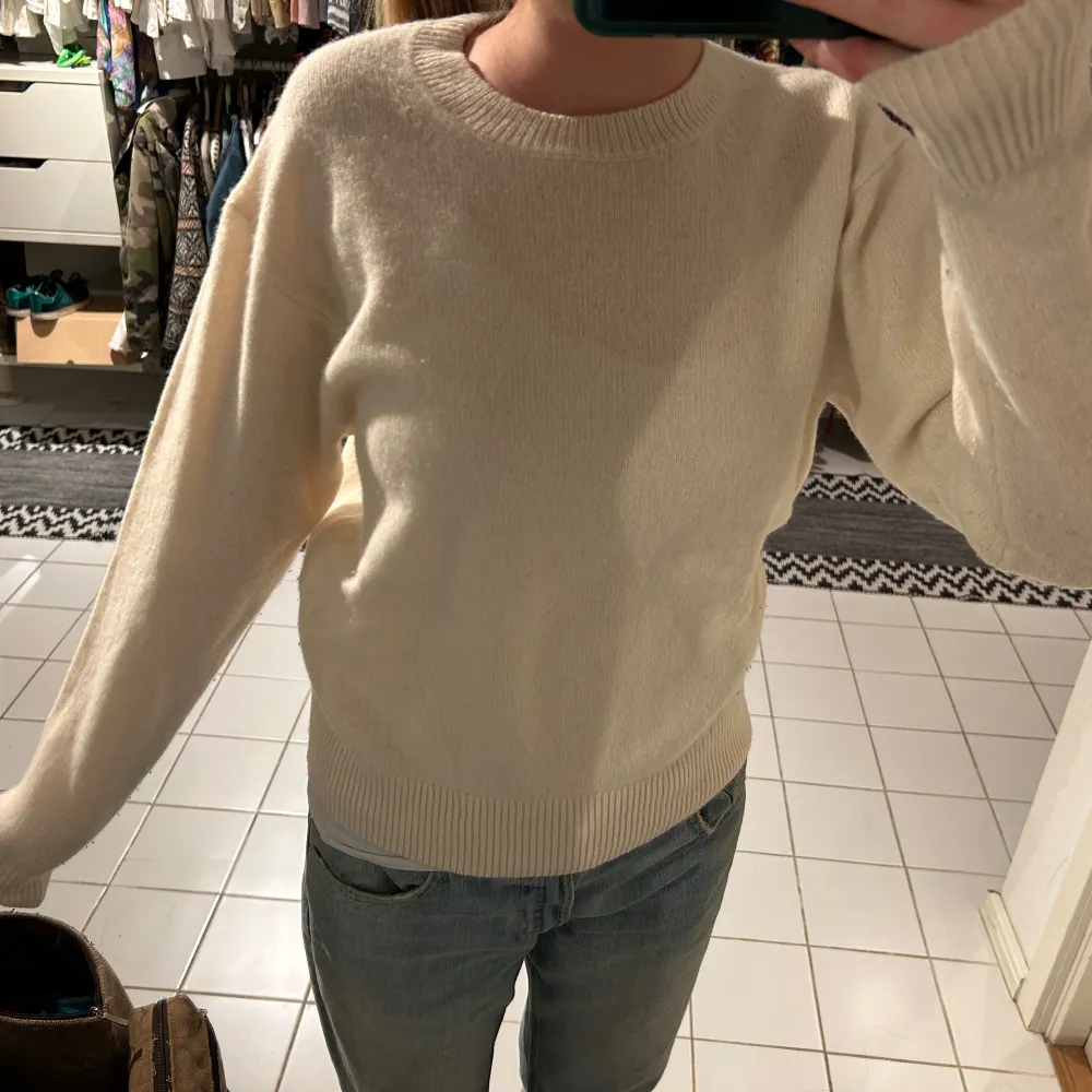 Säljer en stilren vit stickad tröja med rund hals och långa ärmar. Perfekt för kyligare dagar och lätt att matcha med olika outfits. Tröjan har ribbade muddar vid ärmslut och nederkant för en bekväm passform. Från uniqlo. Neuletakit & Villapaidat.