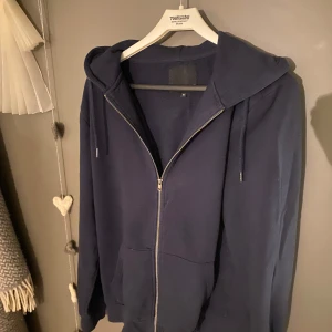 Mörkblå hoodie från 157 - Säljer en mörkblå hoodie från 157 i storlek M. Den har en dragkedja framtill och en praktisk huva med snörning. Perfekt för en avslappnad stil.