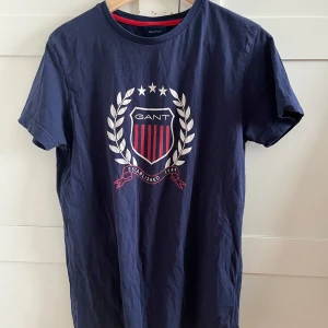 Blå t-shirt från GANT - Snygg blå t-shirt från GANT med ett stort tryck på bröstet. Den är använd att fåtal gånger. Storlek s.