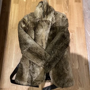 Kappahl Jacka - Säljer en elegant jacka från Kappahl i storlek 36/38. Denna snygga jacka är perfekt för att lägga till en touch av lyx i din garderob. Den är tillverkad av mjuk och lyxig faux fur, och har en perfekt passform. Jackan är helt ny med etiketter kvar. Den är perfekt för både vardag och fest. Missa inte chansen att äga denna fantastiska jacka. Hör av er för mer info/bilder. PRIS KAN DISKUTERAS! 
