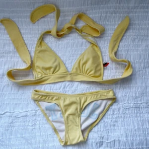 Gul bikini från Juicy Couture - Vet ej om den är äkta eller inte! Snygg gul bikini från Juicy Couture med knytband och texten 'JUICY' i blått på baksidan av trosorna. Perfekt för sommarens stranddagar!