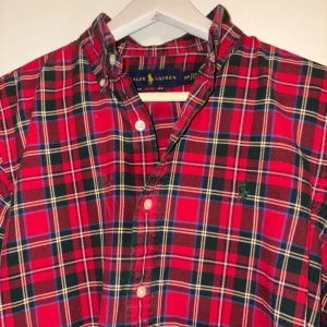 Röd rutig skjorta från Ralph Lauren - Snygg röd rutig skjorta från Ralph Lauren med klassisk krage och knappar framtill. Skjortan har långa ärmar och ett broderat märke på bröstet. Perfekt för en stilren look. Det är en S men tycker snarare det är en M, super fräsch skjorta, som ny. 