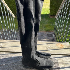 Svarta overknee boots - Snygga svarta overknee boots i mocka med rund tå och snörning baktill. Perfekta för att ge en stilren look.