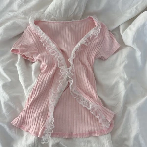 Rosa ribbad topp med spetsdetaljer💕 - Söt rosa ribbad topp med korta ärmar och vacker vit spets längs kanterna. Perfekt för en romantisk look eller en avslappnad dag. 💖
