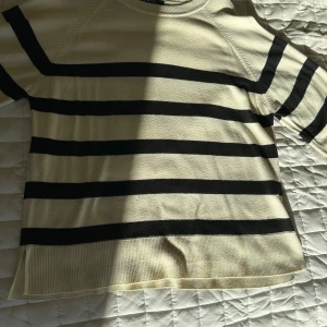 Randig tröja från Gina Tricot - Säljer en snygg randig tröja från Gina Tricot i svart och beige. Tröjan har långa ärmar och en bekväm passform. Perfekt för en stilren look. Hör av dig vid intresse! Är dock nopprig, men det bör gå bort med en nopprare. 
