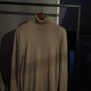 Beige polotröja från Riley - Säljer en stilren beige polotröja från Riley. Perfekt för kyligare dagar med sin mjuka och bekväma passform. Tröjan har långa ärmar och en klassisk polokrage. Passar utmärkt till både jeans och kjol. 🧥✨