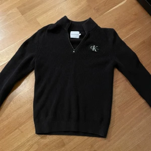 Halfzip Calvin Klein - Säljer en stilren svart stickad quarter zip från Calvin Klein Jeans . Tröjan har långa ärmar och en ribbad krage. Perfekt för våren. Tröjan passar xxs bra också och priset är inte hugget i sten!