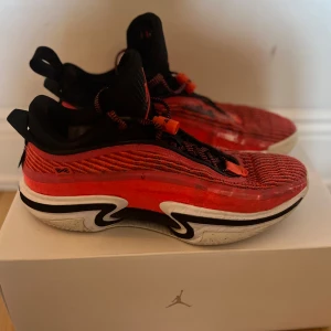 Air Jordan XXXVI Low Infrared - Säljer ett par Air Jordan XXXVI Low i en snygg infraröd färg med svarta detaljer. Skorna har en modern design med snörning och en bekväm sula med Air Zoom-teknologi för extra dämpning. Perfekta för basket eller som en stilren vardagssko. Bra skick bortsett från skadan (kolla bild) Box ingår!