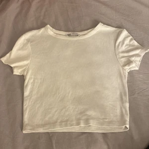Vit kortärmad t-shirt - Säljer en enkel och stilren vit t-shirt. Den är kortärmad och har en rund halsringning. Perfekt basplagg för alla tillfällen!