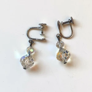 Vintage örhängen med kristallpärlor - Säljer ett par vintage örhängen med skruvstängning och glittrande kristallpärlor. Perfekta för att ge en elegant touch till din outfit. Örhängena har en klassisk design med två facetterade kristaller som fångar ljuset vackert.