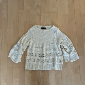 Vit-Beige stickad tröja med trekvartsärmar - Säljer en vit stickad tröja från med spetsdetaljer och trekvartsärmar. Perfekt för en stilren och bekväm look. Tröjan har en lös passform och är idealisk för både vår och sommar. Storlek S