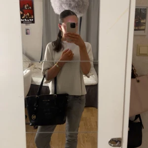 Svart handväska från Michael Kors - Snygg svart handväska från Michael Kors med guldfärgade detaljer och logotyp. Väskan har två handtag och en dragkedja upptill för säker förvaring. Perfekt för att bära dina dagliga nödvändigheter med stil. Perfekt skick förutom lite slitet på remmarna (se sista bilden). Pris kan diskuteras❣️