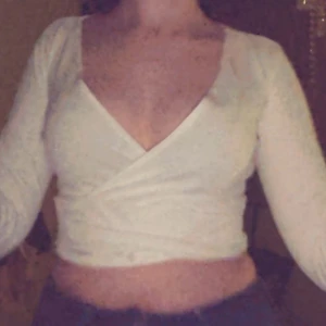 Vit omlottopp från Boohoo - Säljer en stilren vit omlottopp från Boohoo. Toppen har en v-ringad design och långa ärmar, perfekt för en chic look. Passar bra till både jeans och kjol. Perfekt för att uppgradera garderoben! 💫