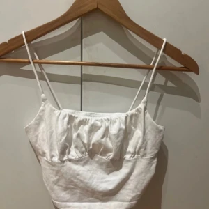 Vit linnetopp från SHEIN stl S - Säljer en söt vit linnetopp från SHEIN med smala axelband och rynkad detalj framtill. Perfekt för varma sommardagar eller som ett lager under en jacka. Toppen är gjord i ett mjukt och bekvämt material.