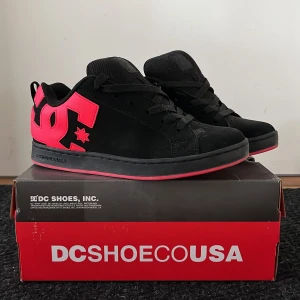 Svarta DC sneakers med rosa detaljer - Säljer ett par svarta DC sneakers med stora rosa DC-loggor på sidorna och rosa detaljer på sulan. Skorna har snörning och en klassisk, rund tå. Säljer då dom är lite småa ( DC skor sitter lite små ) så om du hat st 37-38 kommer dom passa dig perfekt!