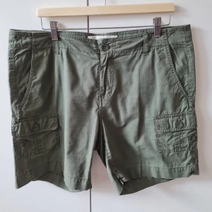 Shorts från H&M strl XL (dam) - Snygga gröna shorts med fickor på sidorna och knappar. Klassisk passform med bälteshällor och knappgylf. Perfekta för sommardagar och avslappnade tillfällen. Material bomull. Storlek XL. Kan hämtas i Vallentuna.