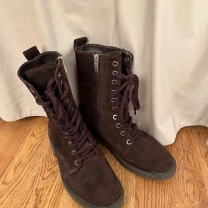 Clarks Kängor, Bruna, 36 - Ett par bruna kängor med snörning och dragkedja på sidan från Clarks i storlek 36. Perfekt för höst och vinter. Äkta läder, mocka. Skorna är i mycket fint skick. Som nya.