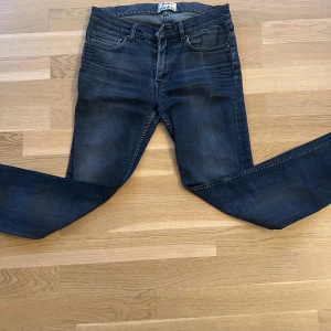 Mörkblå jeansbyxor från Acne Studios - Säljer ett par blåa jeans från Acne studios med klassisk femficksdesign och diskreta slitningar framtill. Jeansen har normal passform och raka ben. Perfekta för en avslappnad stil. Strlk 31-32