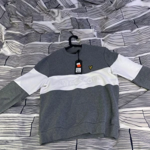 Grå och vit sweatshirt från Lyle & Scott - Säljer en stilren sweatshirt från Lyle & Scott i grått och vitt med logga på bröstet. Tröjan har rund halsringning och långa ärmar. Perfekt för en avslappnad look. Helt ny aldrig använd me prislapp kvar