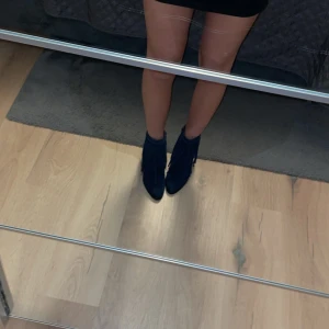 Blå mocka boots med fransar - Säljer ett par snygga blå boots i mocka med fransdetaljer runt skaftet. Skorna har spetsig tå och dragkedja på insidan för enkel påtagning. Perfekta för att ge outfiten en cool touch.