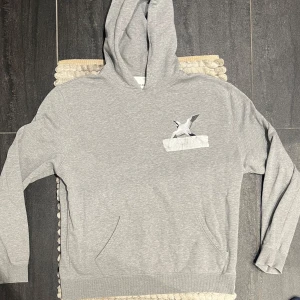 Axel Arigato Hoodie Grå - Grå hoodie från Axel Arigato, storlek M, i fint skick. Stilren och tidlös design med diskret branding – perfekt för dig som gillar minimalistisk och modern streetwear. Mjuk insida, normal passform och kvalitet rakt igenom. Passar både till vardag och som en avslappnad lager-på-lager-look. 