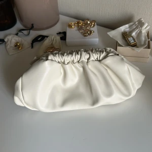 Vit kuvertväska från Gina Tricot - Stilren vit kuvertväska från Gina Tricot i mjukt syntetmaterial. Väskan har en rynkad öppning och minimalistisk design, perfekt att bära i handen. Enkel att matcha med olika outfits. Aldrig använd! 💞