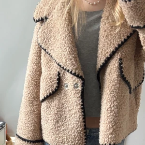 Beige teddyjacka från Object - Beige teddy jacka med svarta detaljer från Objekt. Använt 1 gång, nypris 1250