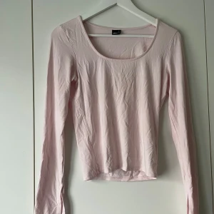 Ljusrosa långärmad topp från Gina Tricot - Säljer en ljusrosa långärmad topp från Gina Tricot. Toppen en slits detalj på slutet av ärmen och är tillverkad i ett mjukt, stretchigt material. Perfekt att styla med jeans eller kjol för en enkel och fräsch look.