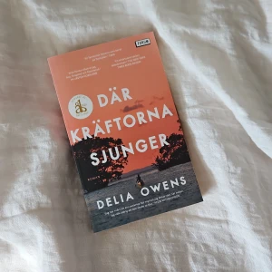 Där kräftorna sjunger - En roman av Delia Owens med ett omslag i orange och svart, föreställande en siluett av en person vid vatten i solnedgång. Boken är på svenska och har fått utmärkelsen Årets Bok. Perfekt för dig som gillar gripande berättelser och natur.