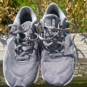 Grå Nike sneakers med vit sula - Säljer ett par grå Nike sneakers med vit och svart sula. Skorna har mesh-ovandel för bra ventilation och klassisk snörning. Perfekta för vardagsbruk eller träning. Swoosh-logga på sidan och bekväm passform.