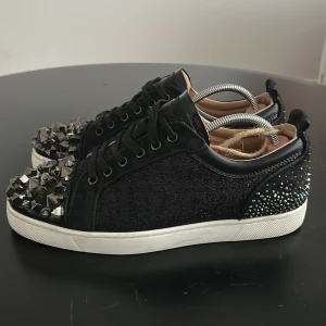 Christian Louboutin sneakers - Säljer ett par riktigt sällsynta och unika svarta Christian Louboutin och swarovski sneakers med glittriga sidor och silverfärgade nitar på tån dekorerade med riktiga swarovski kristaller där bak. Skorna kostar runt 2000€ nya vilket motsvarar ungefär 20000 och är riktigt sällsynta vilket gör det perfekta skor om du vill stå ut från alla andra! Skorna är limited edition och finns få av, DM:a mig vid minsta frågor/funderingar och om du är intresserad i dojorna! 