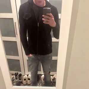 Svart stickad tröja från Esprit - Säljer en svart stickad tröja från Esprit med dragkedja och två bröstfickor med knappar. Jackan har hög krage och ribbade detaljer vid ärmslut och nederkant. Bara höra av sig vid funderingar!