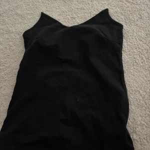 Svart linnetopp  - Säljer en svart enkel linnetopp i mjuk bomullsblandning med stretch. v-ringad halsringning, perfekt för sommardagar eller som lager under andra plagg. Axelbanden avklippta