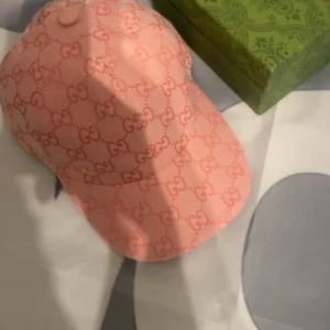 Rosa keps - Säljer en rosa keps med klassiskt GG-mönster över hela kepsen. Kepsen har böjd skärm och justerbar passform. Perfekt accessoar för att lyfta din outfit.