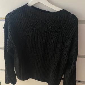 Svart stickad tröja från Hollys - Säljer en svart stickad tröja från Hollys. Tröjan har ett grovt stickat mönster och rund halsringning. Perfekt för kyligare dagar och enkel att matcha med olika outfits.