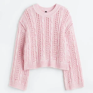 Ljusrosa stickad tröja från Divided - Superfin ljusrosa stickad tröja från Divided med kabelstickat mönster och croppad passform. Tröjan har långa ärmar och rund halsringning. Perfekt för lager-på-lager och mysiga dagar. Liknar den på bilderna.