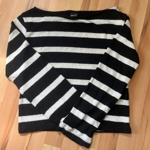Svartvit randig off-shoulder tröja från Gina Tricot  - Säljer en svart och vit randig tröja från Gina Tricot i storlek XS. Tröjan har långa ärmar och en klassisk rak passform. Sitter off shoulder 