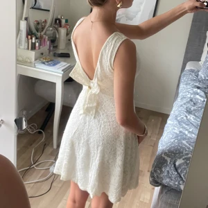 Vit spetsklänning med öppen rygg, rosett och inbyggd bh! - Säljer en söt vit spetsklänning med rund halsringning och öppen rygg. Klänningen har en rosett bak i midjan och är ärmlös med en lätt utställd kjol. Perfekt för sommarens tillfällen och även studenten! Pris kan diskuteras.