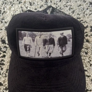 Svart keps från Emilio Poniocza med vintagefoto - En svart stelren keps från emilio pendenza. Den är 9/10 i skick med är lite trasig vid spännet. 