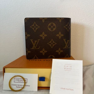 Brun plånbok från Luviton - Snygg brun plånbok från Luviton med monogrammönster i guld. Plånboken har massa fack för kort och sedlar. Perfekt för dig som gillar lyxiga detaljer och maxa din stil. Nästan helt oanvänd och är helt ren. PRISET KAN DISKUTERAS.