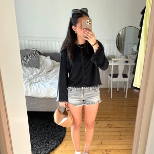 Svart långärmad topp med spetsdetaljer från Bershka - Säljer en svart långärmad topp från Bershka med fina spetsdetaljer längs nederkanten, ärmsluten och framtill. Toppen är perfekt att styla till både jeans och kjol. Enkel och stilren design.🩷