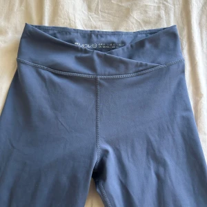 Blå träningsthights från HM - Säljer ett par blå leggings från HM med mid hög midja och smal passform. Byxorna har en stilren design utan synliga detaljer och är perfekta för träning eller en avslappnad look.
